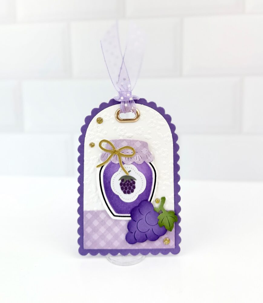 Decorative purple gift tag with lavender ribbon, grape motif, and floral embossing on a white panel.